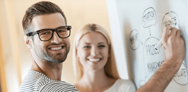 Smilende mann skriver på tavle 